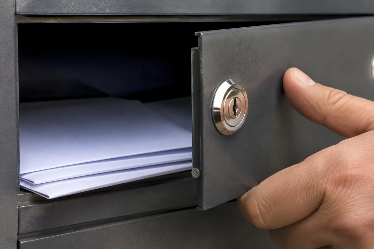 Détail d&rsquo;une serrure de boîte aux lettres et d&rsquo;une porte ouverte sur du courrier